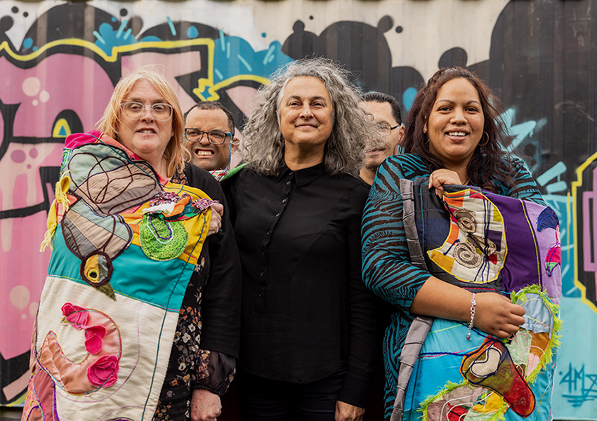Three women smiling infront of grafffiti art