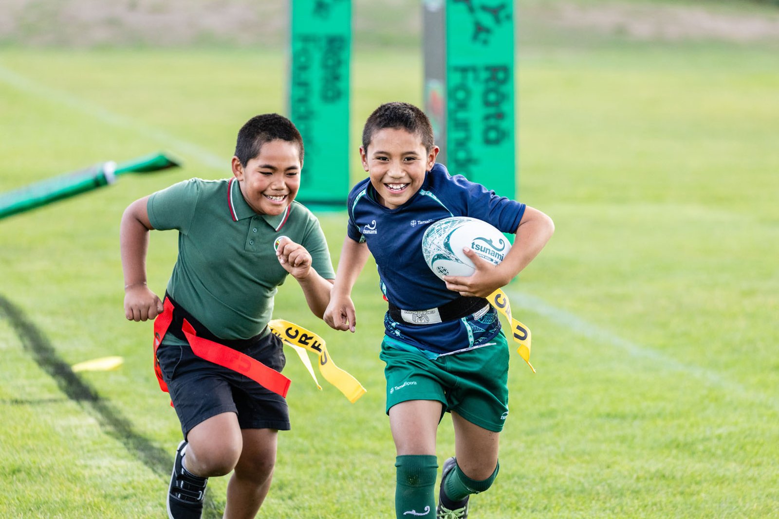 Two boys running with a rugby ball